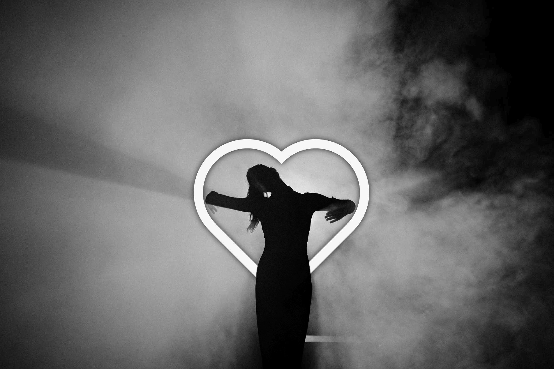 A black and white image shows a silhouette of a person with arms outstretched in front of a heart-shaped outline, against a misty background.